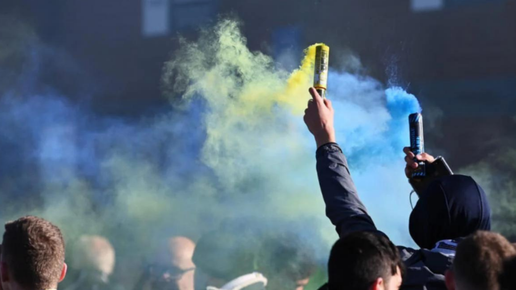 Leeds United fans light blue and yellow smoke bombs